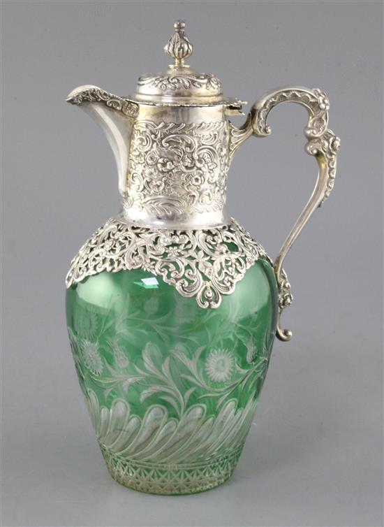 A late Victorian pierced repousse silver mounted green and clear cut glass claret jug by William Comyns, London, 1897, 26cm.